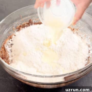 Creamy Nutella Hazelnut Buttercream 7 Milk being poured into the glass bowl with the frosting ingredients.