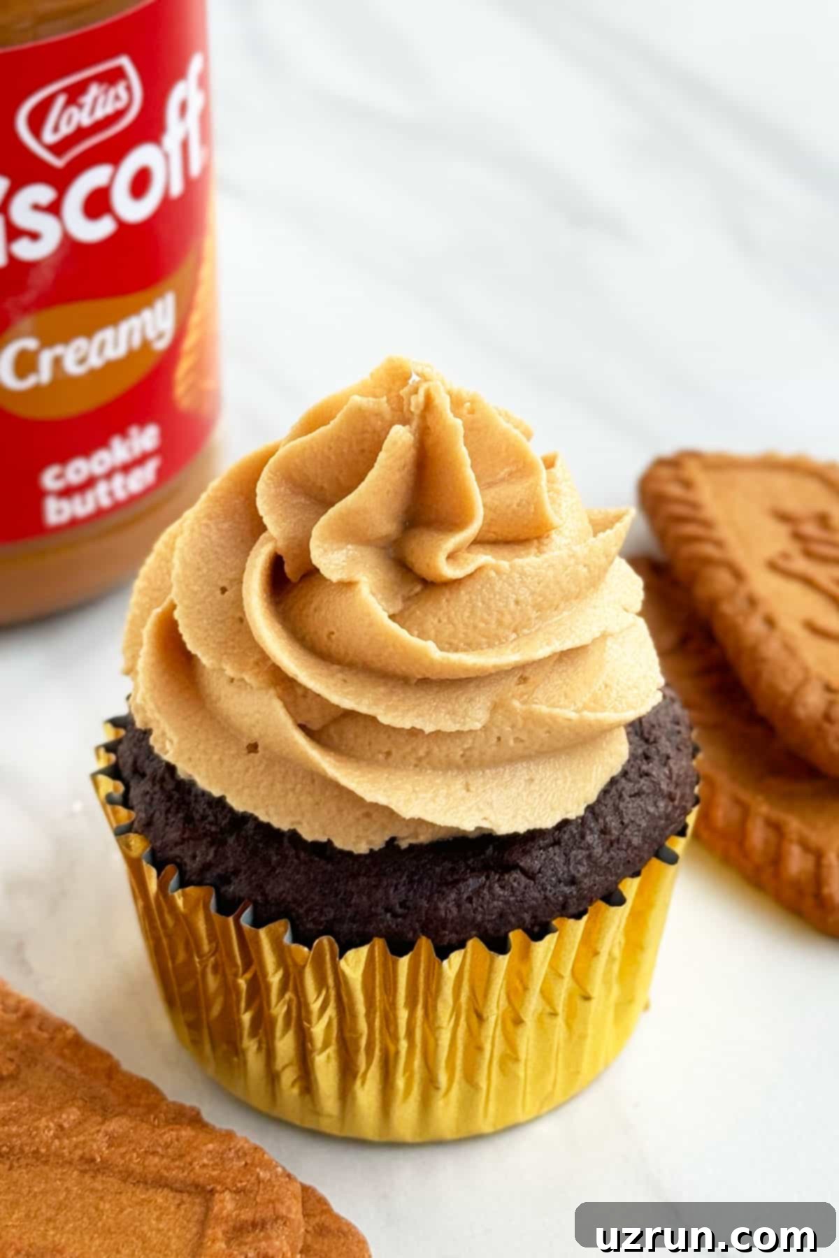 Easy Biscoff Cupcakes With Chocolate Cake Mix Box in Golden Liners on White Marble Background. Each cupcake is perfectly baked and ready for frosting.