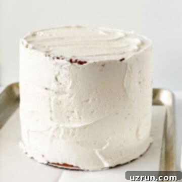 Three cake layers stacked and covered in white buttercream. 