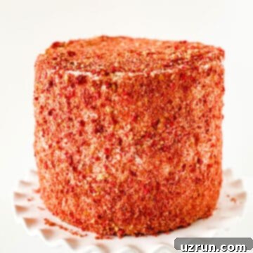 Iced cake covered in pink crunchy topping. 