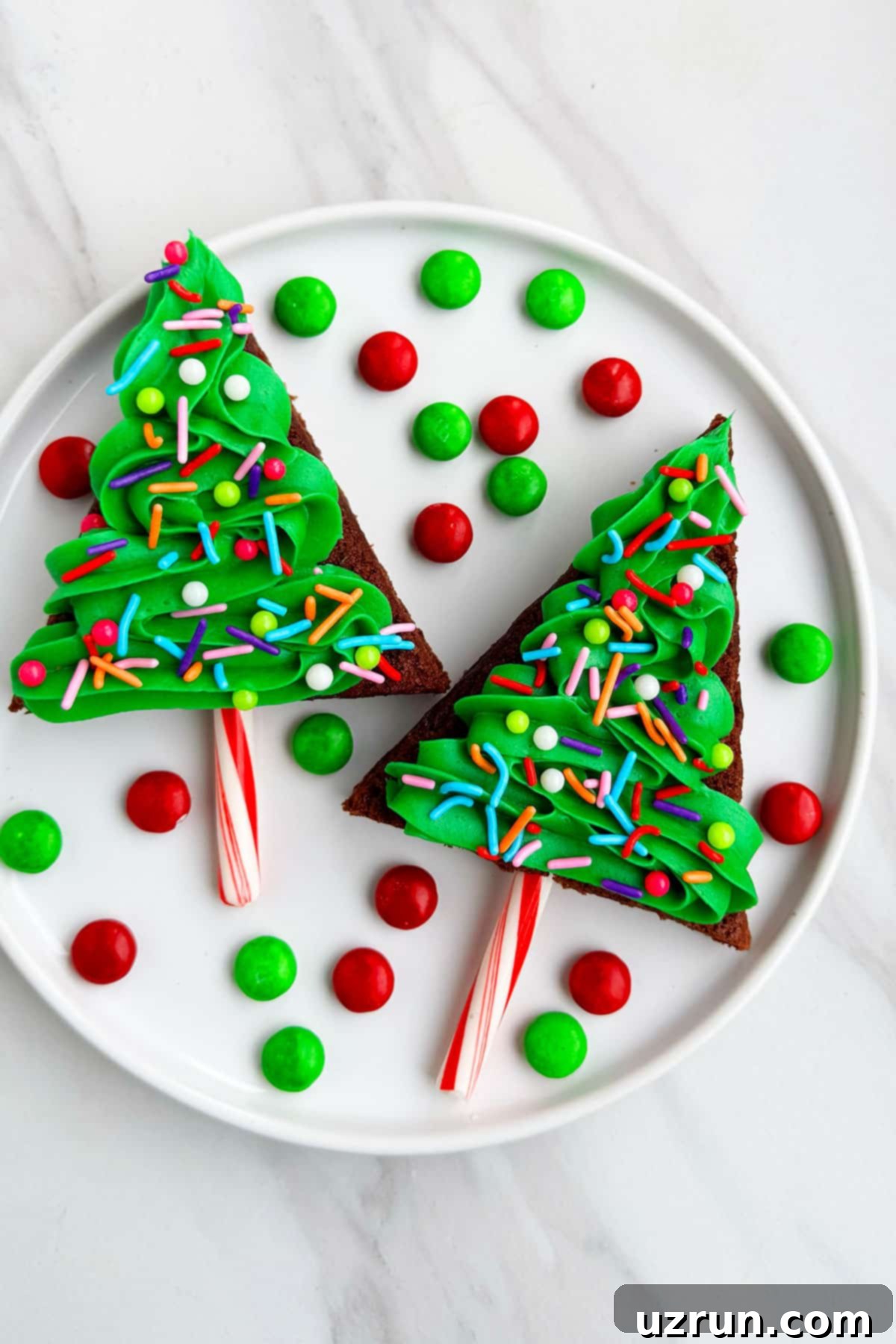 Christmas Tree Brownie Bites 3 Easy Homemade Christmas Brownie Bites on White Dish With M&M Candies Scattered Around.