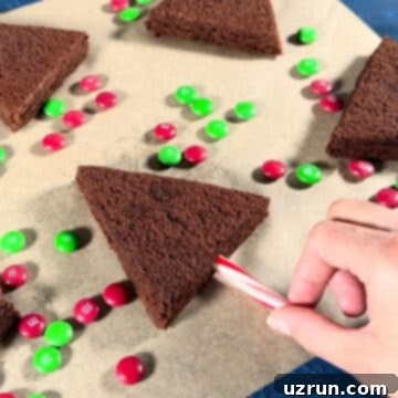 Christmas Tree Brownie Bites 6 Candy cane being pushed into the base of the brownie.