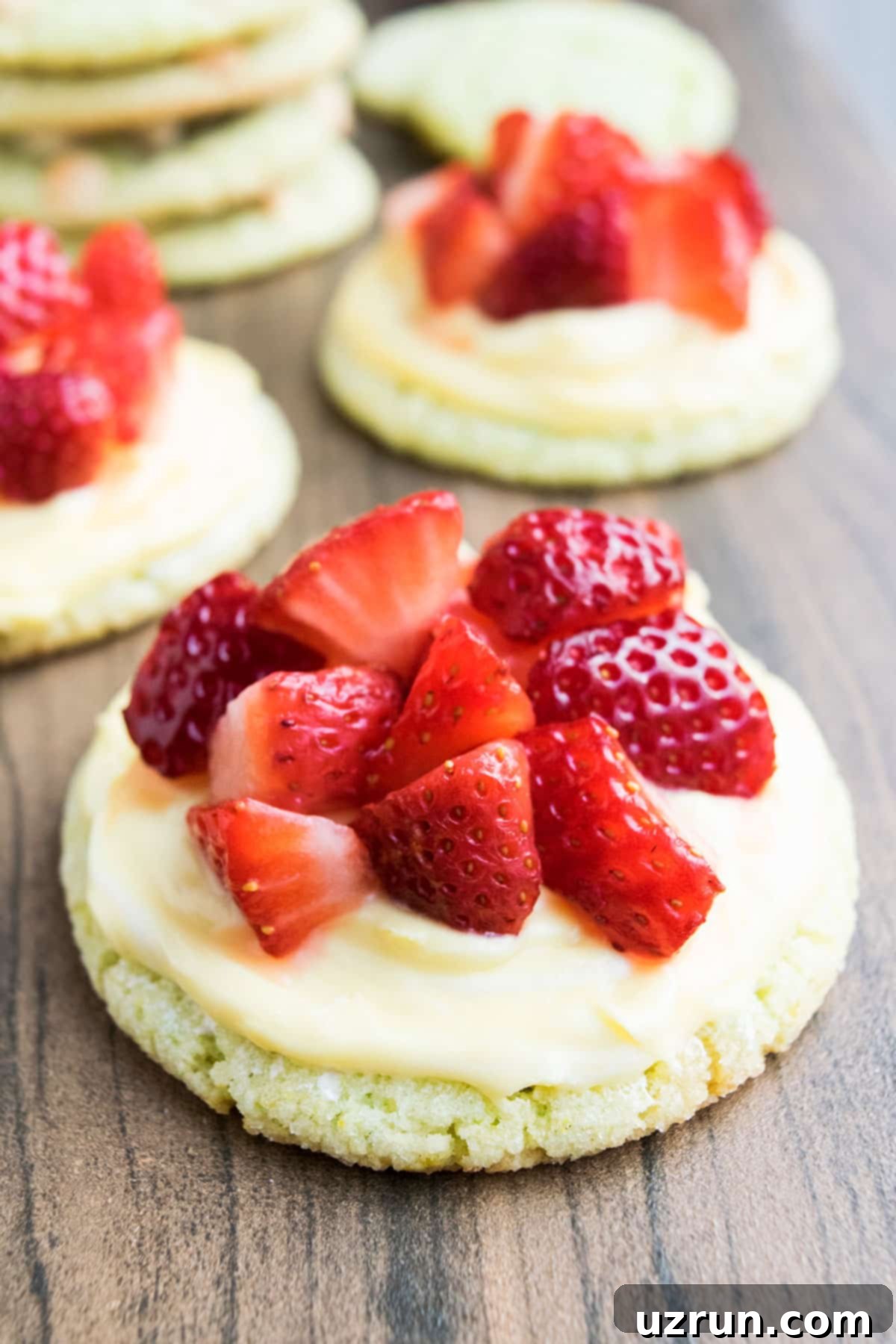 Zesty Key Lime Crinkle Cookies 5 Frosted Key Lime Pie Cookies With Fresh Sliced Strawberries on Wood Background.