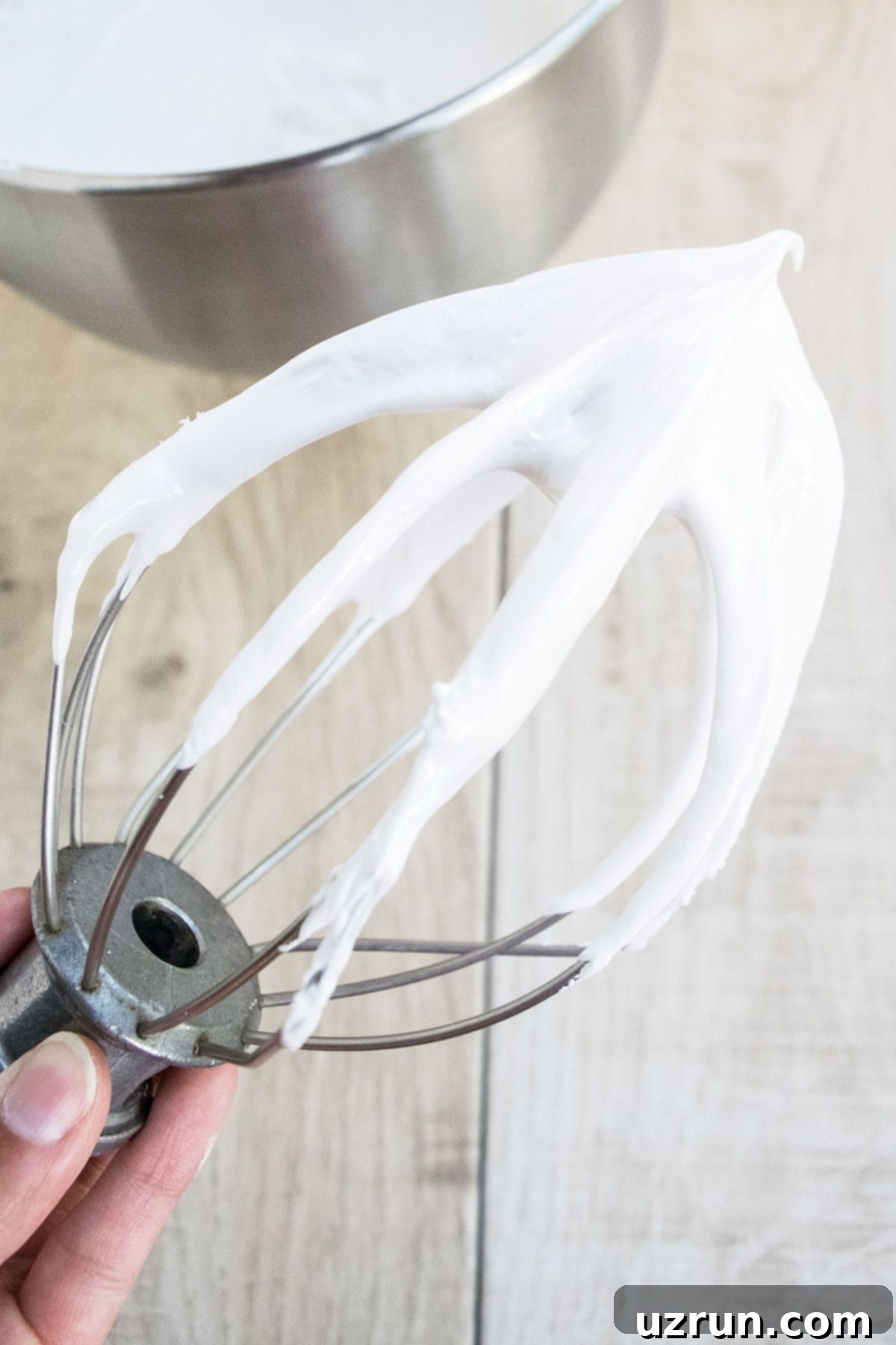 Whisk With Easy Seven Minute Frosting on Light Brown Background.