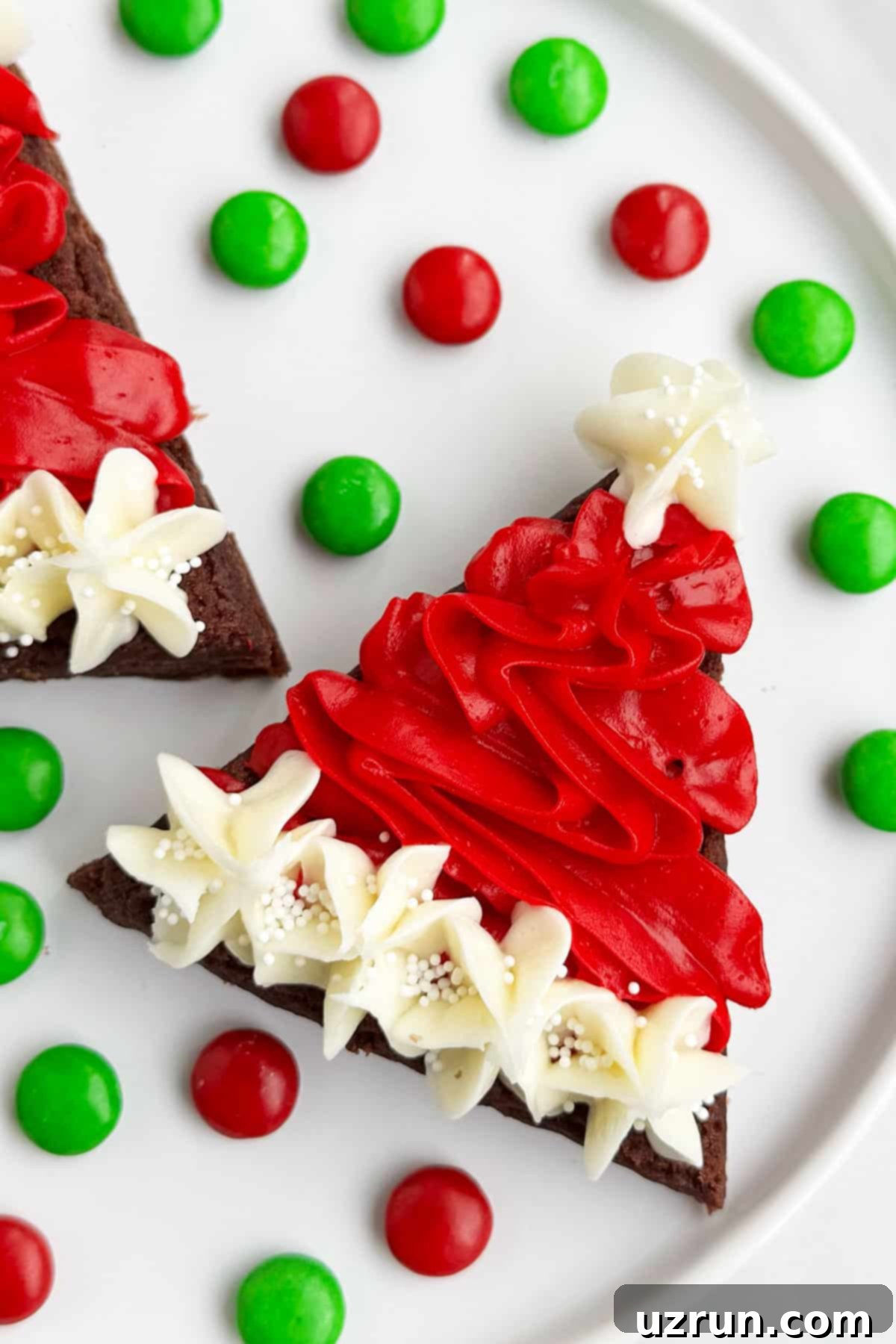 Easy Santa Hat Brownies With Buttercream Frosting For Christmas on White Dish. A platter of fudgy chocolate brownies decorated as Santa hats with red and white buttercream, perfect for festive holiday dessert.