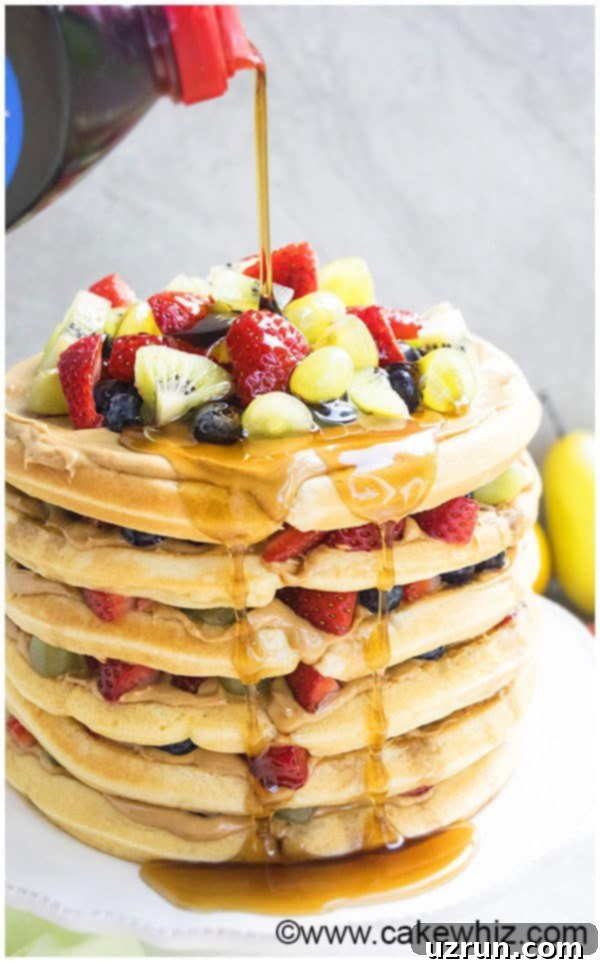 Easy Waffle Cake with Pancake Syrup Being Poured on Top, garnished with fresh fruits.