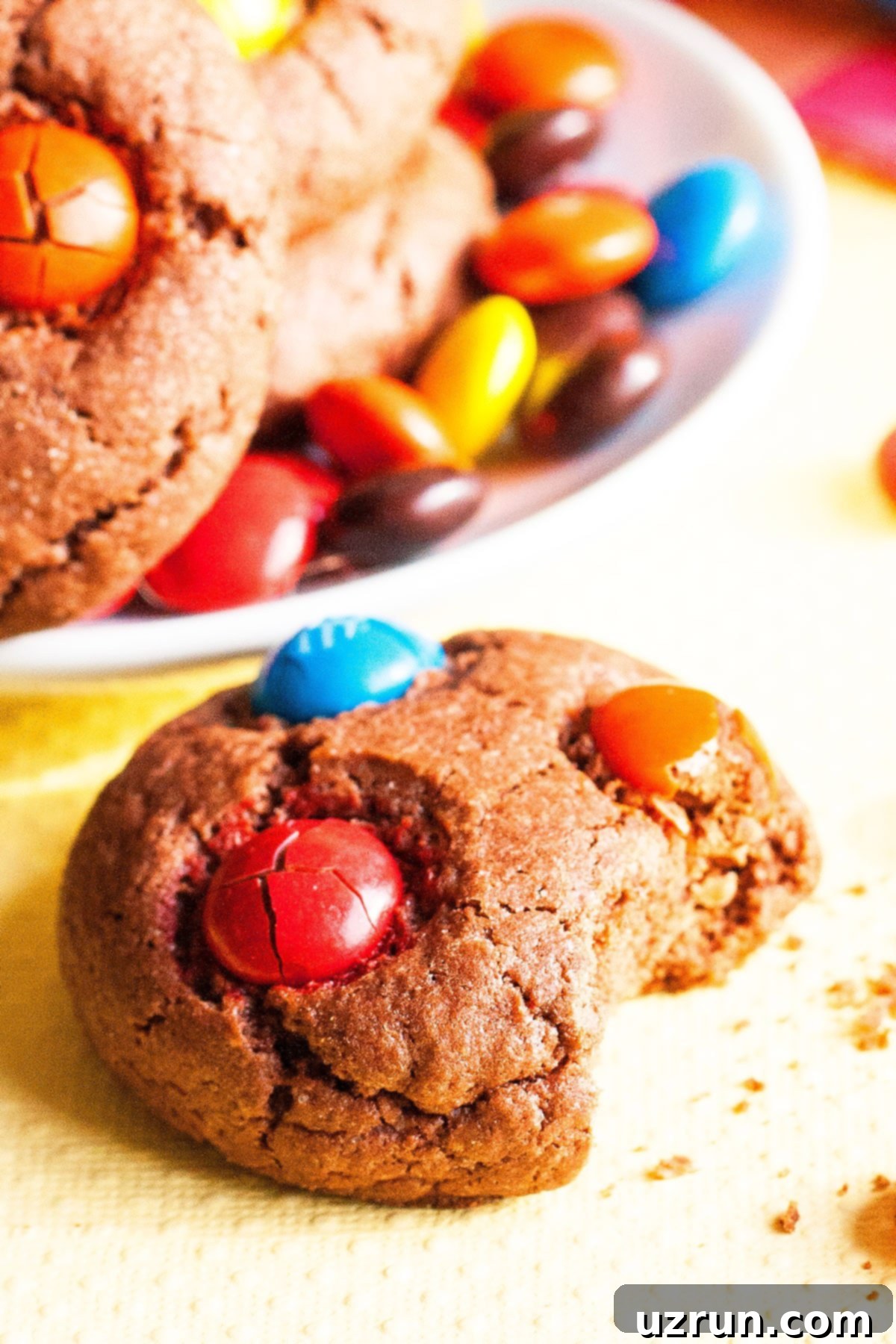 Easy Chocolate M and M Cake Mix Cookies 4 Partially Eaten Cookie on Yellow Background.