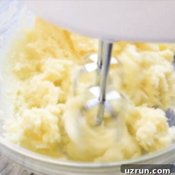 Easy Two-Ingredient White Chocolate Buttercream 6 Butter and white chocolate being whipped in glass bowl.