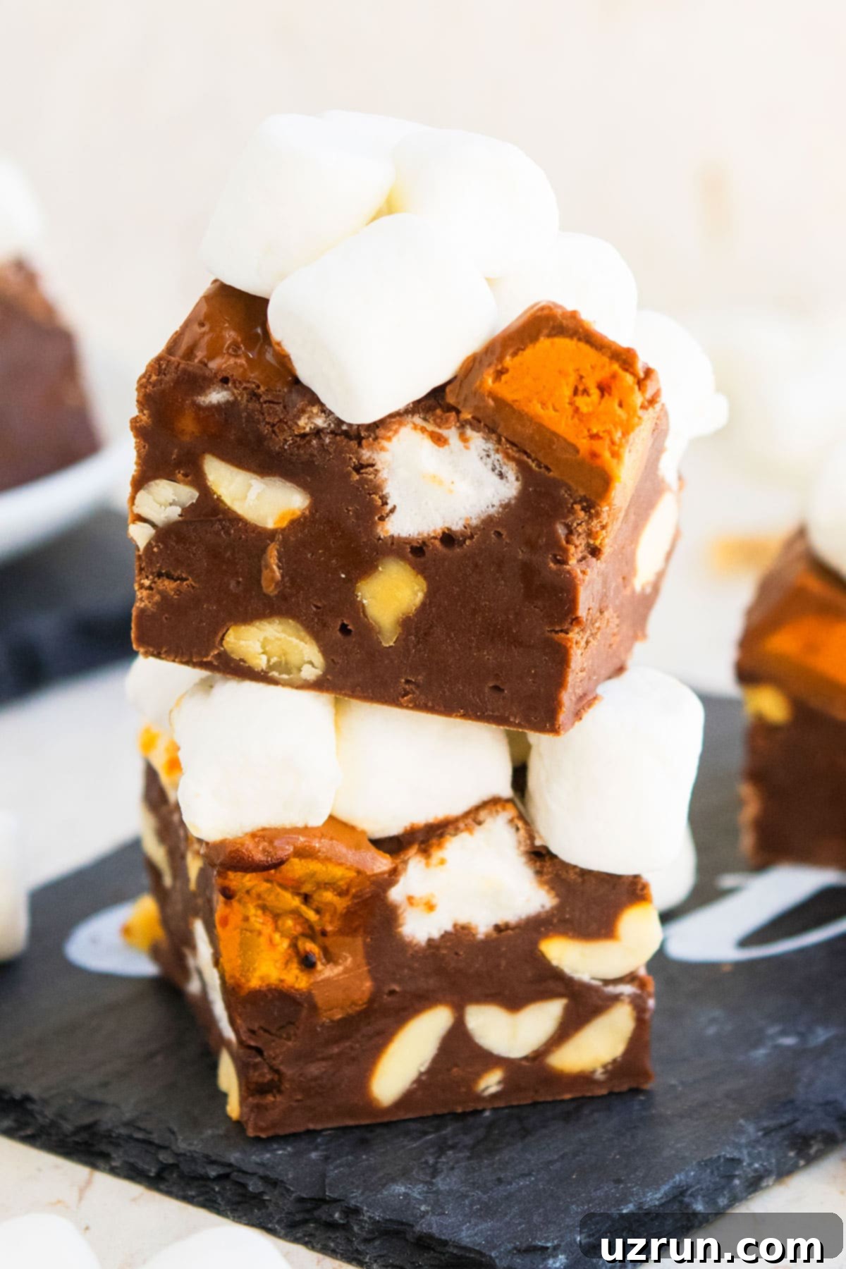 Stack of Rocky Road Fudge Slices on Black Dish With Off White Background. 