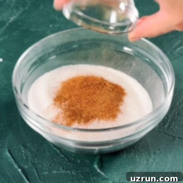 Effortless Homemade Cinnamon Sugar 5 Ground cinnamon being added to other ingredient in glass bowl.