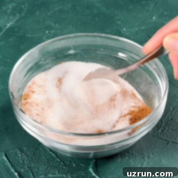 Effortless Homemade Cinnamon Sugar 6 Ingredients being mixed together with spoon in glass bowl.