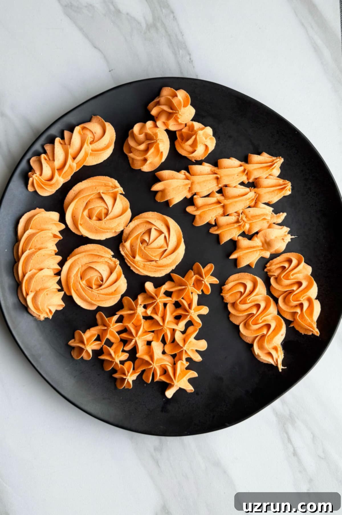 Easy Pumpkin Cream Cheese Frosting 11 Piped frosting designs on a black dish.