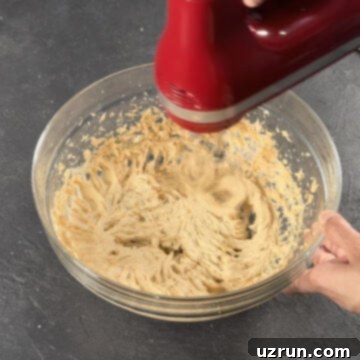 Easy Pumpkin Cream Cheese Frosting 6 Ingredients being mixed together in glass bowl with red hand held mixer.