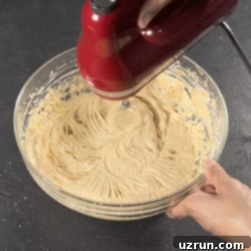 Easy Pumpkin Cream Cheese Frosting 8 Smooth icing being mixed together with red hand held mixer.
