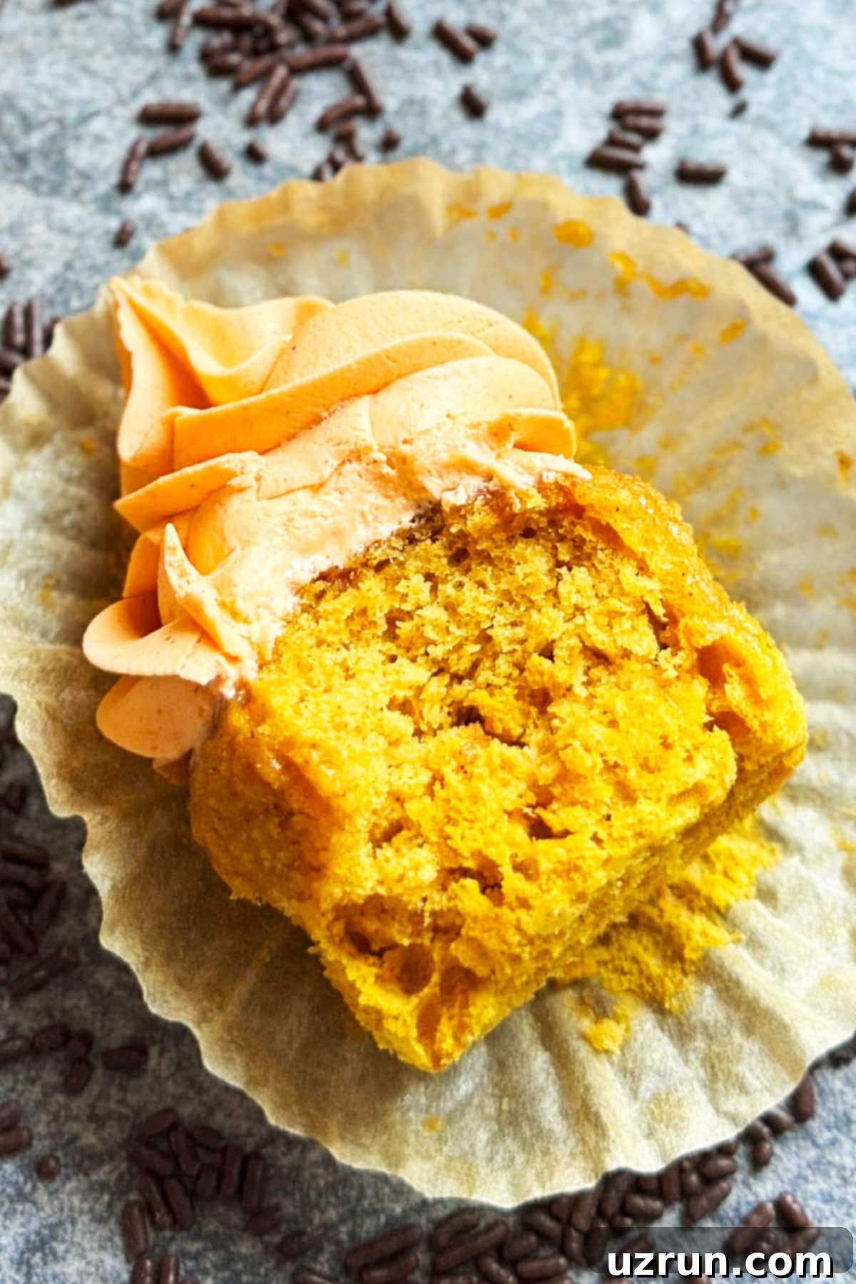 Cozy Pumpkin Cupcakes with Spiced Cream Cheese Frosting 11 Partially eaten cupcake on peeled liner.