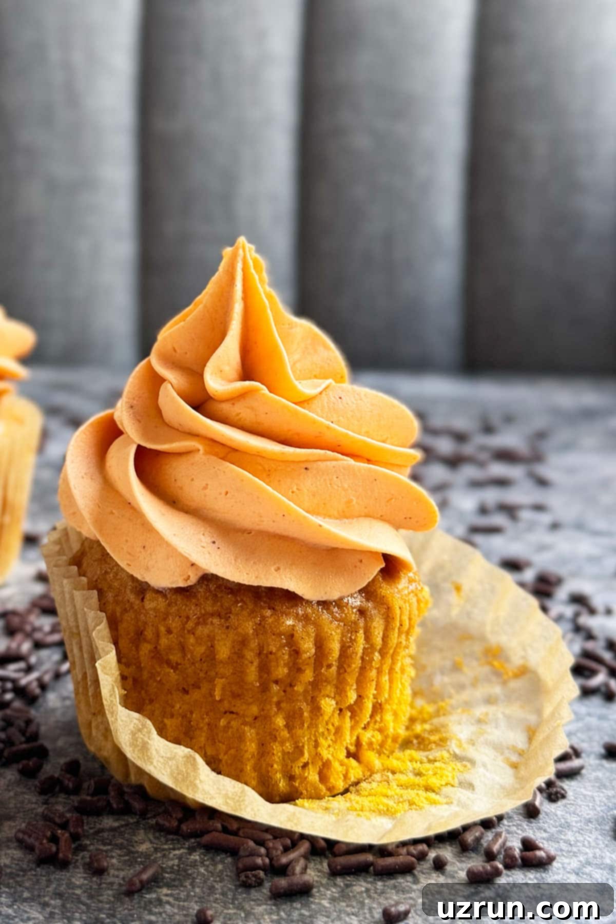 Cozy Pumpkin Cupcakes with Spiced Cream Cheese Frosting 4 Frosted spiced cupcake with liner partially peeled.