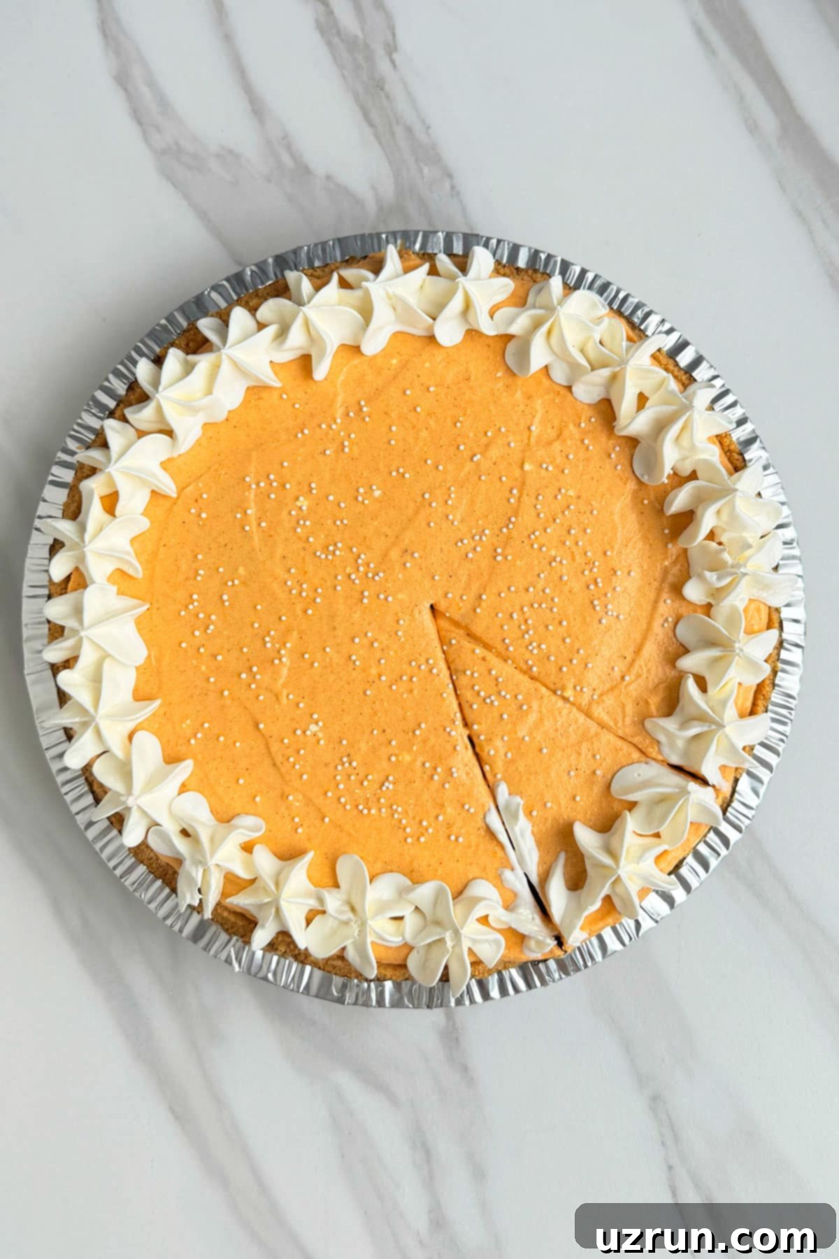 Velvet Pumpkin No-Bake Cheesecake 2 Easy No Bake Pumpkin Pie on White Marble Background With a Slice Cut Out.