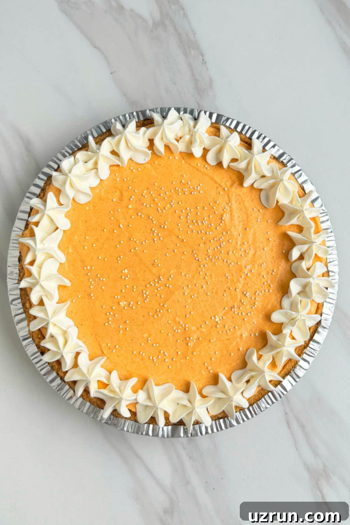 Velvet Pumpkin No-Bake Cheesecake 13 Best Homemade No Bake Thanksgiving Pie on White Marble Background- Overhead Shot.