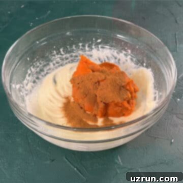 Velvet Pumpkin No-Bake Cheesecake 6 Pumpkin puree and pumpkin pie spiced added to cheese mixture in glass bowl.