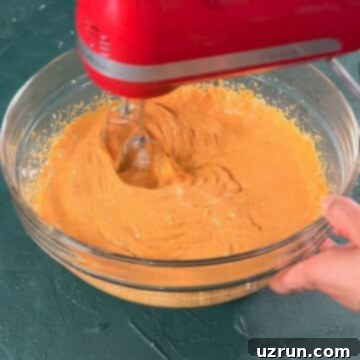Velvet Pumpkin No-Bake Cheesecake 7 Pumpkin cheesecake mixture being mixed with hand held mixer.