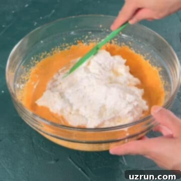 Velvet Pumpkin No-Bake Cheesecake 8 Whipped cream being folded into mixture in glass bowl.