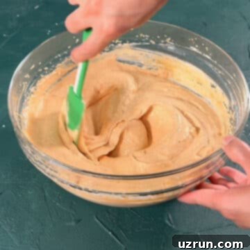 Velvet Pumpkin No-Bake Cheesecake 9 Green spatula being used to mix ingredients.