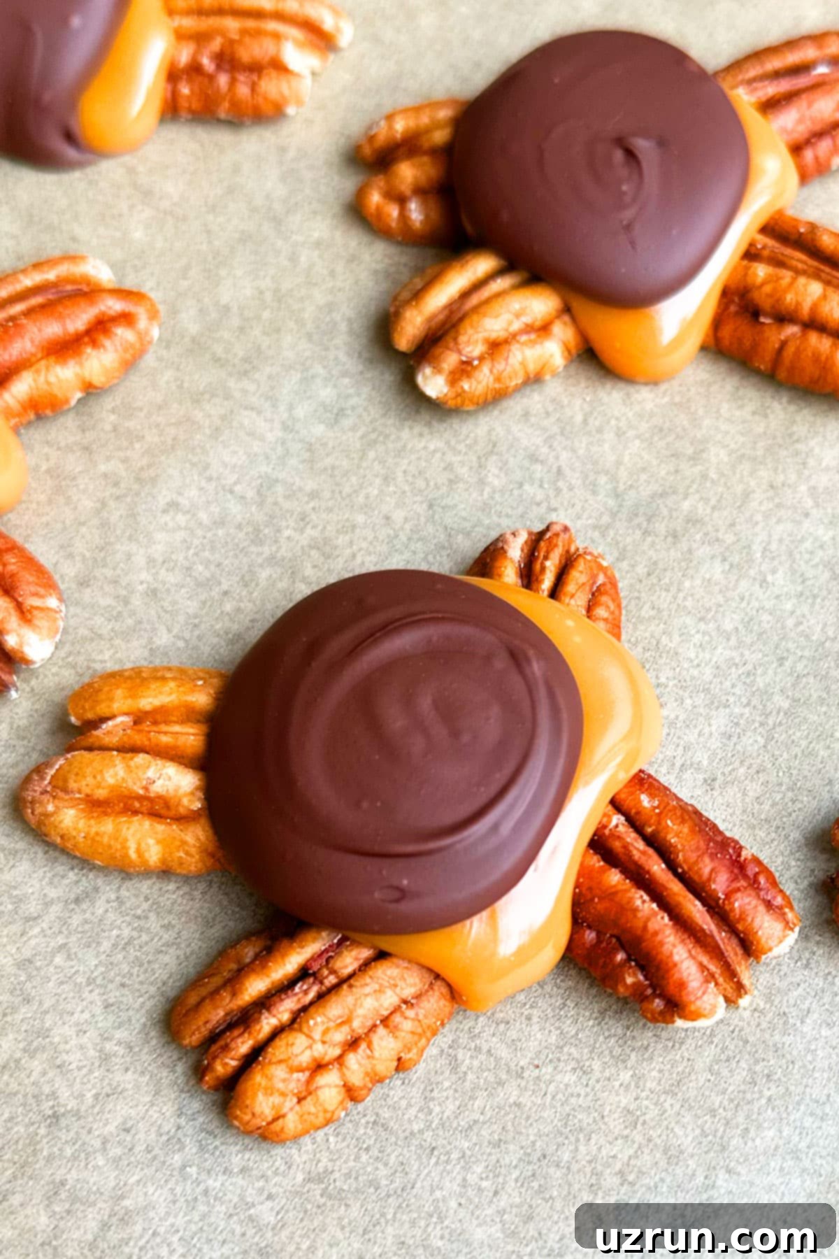 Decadent Homemade Chocolate Caramel Pecan Turtles 4 Closeup Shot of Chocolate Caramel Pecan Cluster on Brown Wax Paper.