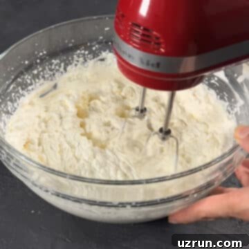 No-Bake Spiced Chai Tiramisu Cake 6 Mascarpone filling being whipped in a glass bowl with hand held mixer.